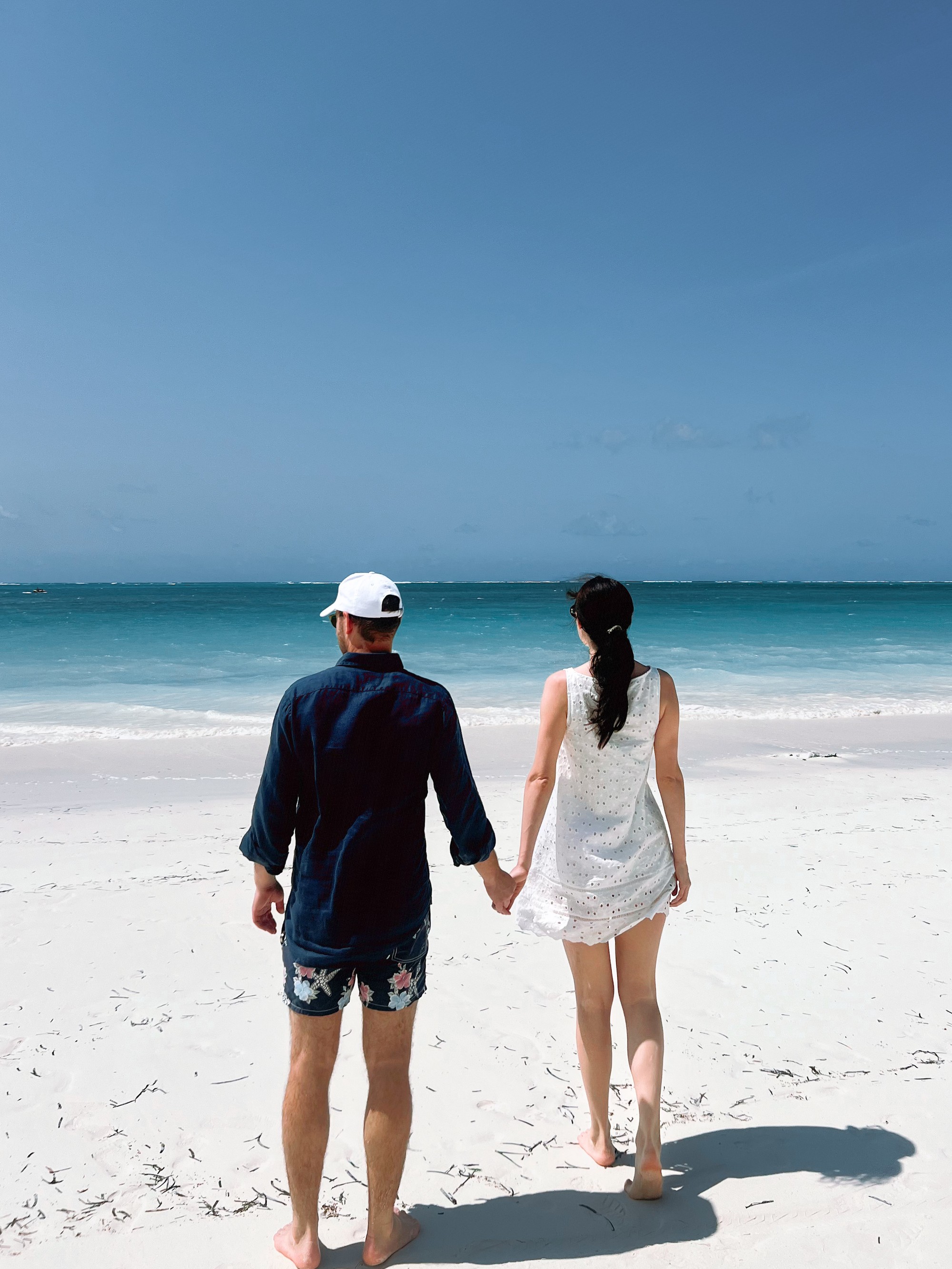 Neža and Miha holding hands as they walk towards a tropical beach